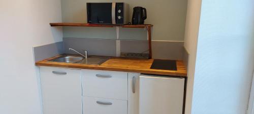 une petite cuisine avec des armoires blanches et un évier dans l'établissement Studio à la Petite Boissière proximité des plages et de la gare SNCF, à Pluguffan