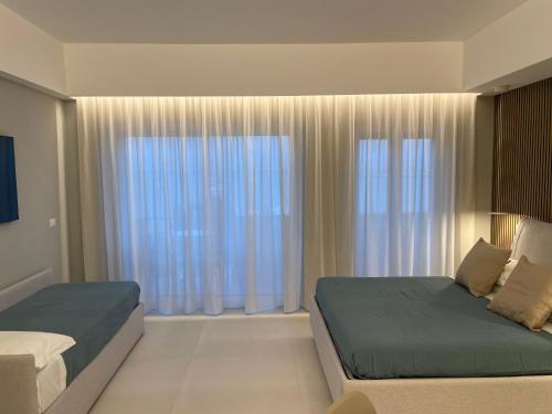a bedroom with two beds and a large window at La Finestra sul Mare Modern Apartment in Giardini Naxos