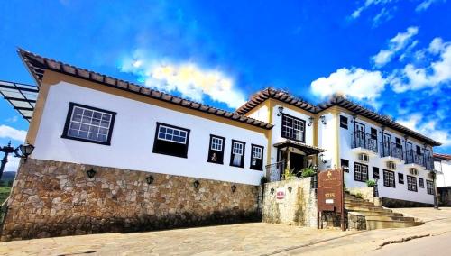 a large white house with a stone wall at Pousada Dom Xavier in Tiradentes