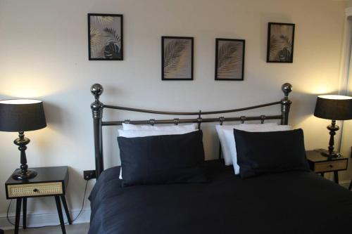 a bedroom with a black bed with three pictures on the wall at Urban Oasis: North London in Edmonton