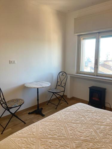 een slaapkamer met een bed en 2 stoelen en een tafel bij Attico Verdi in Gorizia