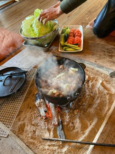 a person cooking food in a wok on a table at 竜野園藝 in Kamimashiki