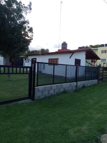 a fence in front of a field with a house at Cabañas "Las Acacias" in Villa Santa Cruz del Lago