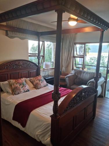 a bedroom with a canopy bed and a couch at Lagoon Breeze Guest House in Knysna