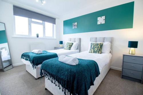 um quarto com duas camas com capas verdes em *3Bed House Central location Free Parking Perfect for contractors & groups Managed by Chique Properties Ltd em Great Linford