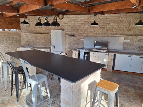 a kitchen with a large black counter and chairs at La Maison du Moulin de Tartay in Avignon