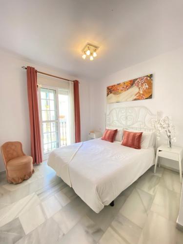 a white bedroom with a large bed and a chair at La Pimentera Casco Antiguo - Marbella in Marbella