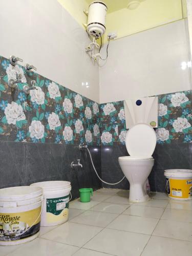 a bathroom with a toilet and flowers on the wall at Hotel Old Moon Cafe in Pushkar