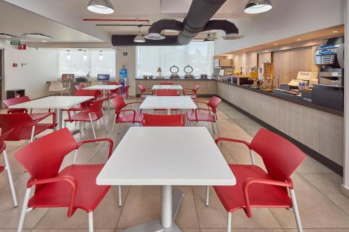 a restaurant with white tables and red chairs at City Express Junior by Marriott Mexicali in Mexicali