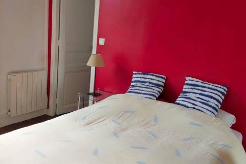 a bedroom with a red wall and a bed with blue pillows at Sunny Serenity: 2-room Charm in Boulogne in Boulogne-Billancourt