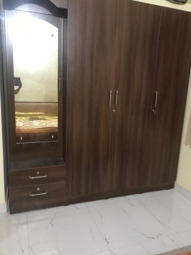 a wooden cabinet with a mirror in a room at Kushi guest house in Bangalore