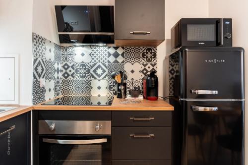 a kitchen with a black refrigerator and black and white tiles at Road to Disney by Plaza in Montévrain