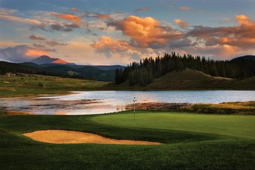 a golf course with a lake and a golfer on the green at River Run Village by Keystone Resort in Keystone