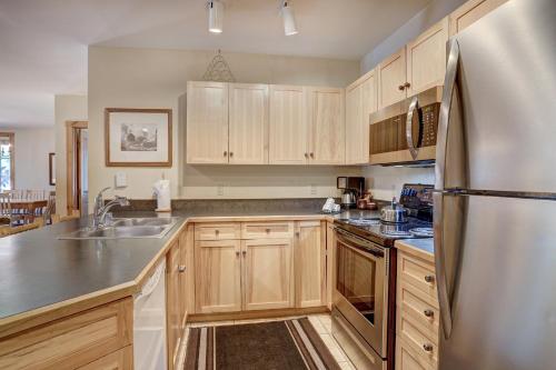 a kitchen with wooden cabinets and a stainless steel refrigerator at River Run Village by Keystone Resort in Keystone