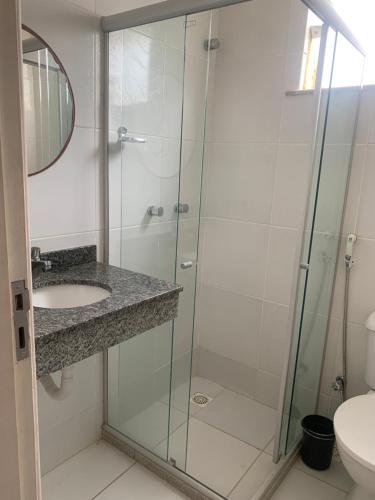 uma casa de banho com uma cabina de duche em vidro e um lavatório. em VIRASSOL Praia Hotel em Salvador
