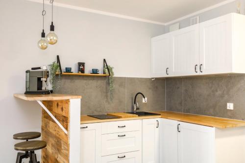 a kitchen with white cabinets and a sink at River House - J&D Apartamenty in Szczecin