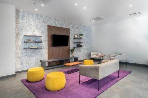 a living room with a couch and chairs and a tv at City Express by Marriott Mérida in Mérida