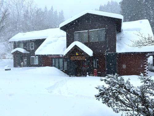 a house covered in snow in the yard at Mominoki Lodgeモミの木ロッジ in Minakami