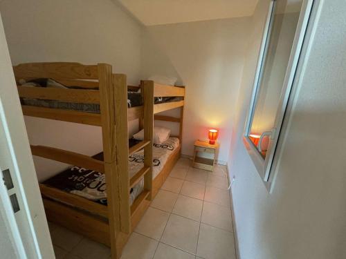 Cette petite chambre comprend des lits superposés et une lampe. dans l'établissement Studio cabine neuf avec terrasse proche plage et centre, parking privé inclus - FR-1-250-185, au Grau-du-Roi