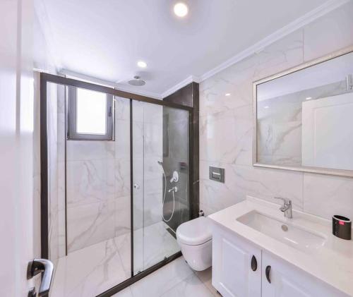 een badkamer met een douche, een toilet en een wastafel bij TOBİ APART 2 / MERKEZİ KONUMDA LÜKS DAİRE in Kas