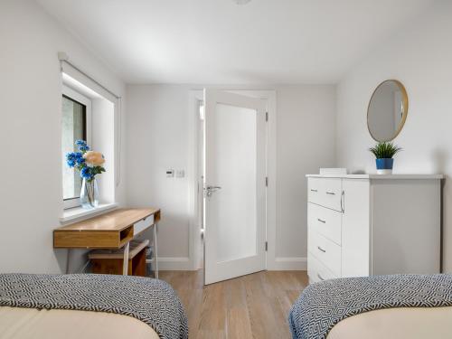 1 dormitorio con 2 camas, escritorio y espejo en Cleggan Pierside Apt 2, en Cleggan