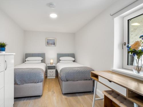 1 dormitorio con 2 camas, mesa y ventana en Cleggan Pierside Apt 2, en Cleggan