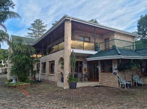 a brick house with a balcony and a patio at Lagoon Breeze Guest House in Knysna