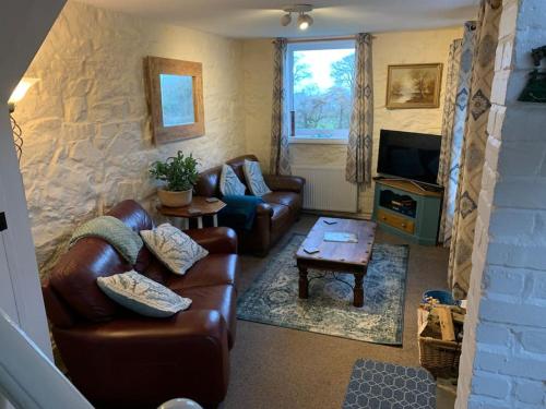 a living room with leather couches and a tv at Cosy Two Bedroom Cottage with Fireplace in Colwyn Bay