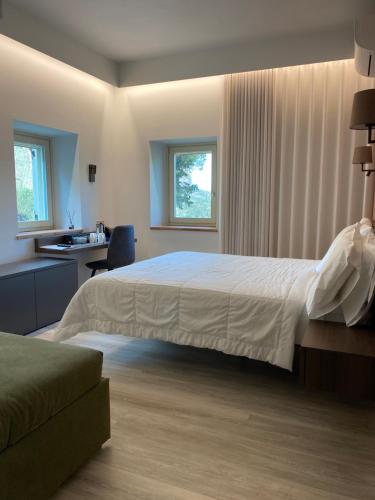 um quarto com uma grande cama branca e uma secretária em Colle Serrano Relais & SPA em Ripatransone