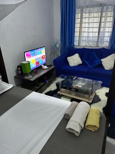 un salon avec un canapé bleu et une télévision dans l'établissement Diani cozy studio apartment, à Ukunda