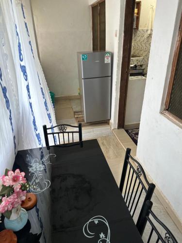 Cette chambre comprend une table, des chaises et un réfrigérateur. dans l'établissement Diani cozy studio apartment, à Ukunda