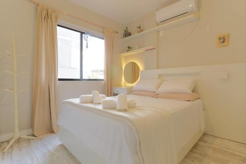 um quarto com uma grande cama branca e uma janela em Lindo e Confortável a 100m da Praia dos Amores JG9086 em Itajaí
