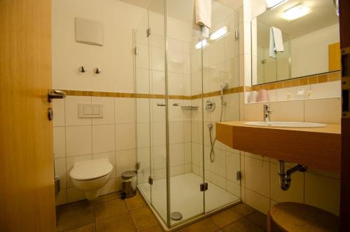 y baño con ducha, aseo y lavamanos. en s`Wirtshaus Hotel & Restaurant en Oberammergau