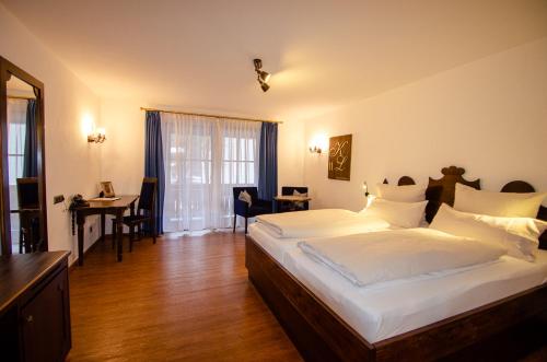 a bedroom with a bed and a desk and a table at s`Wirtshaus Hotel & Restaurant in Oberammergau