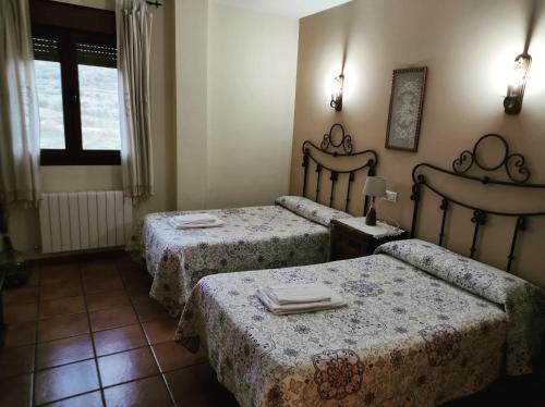 a room with two beds with tables and a window at Casa Rural Los Olivos in Sotoserrano