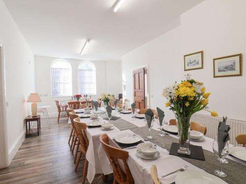 The Power House في Loftus: غرفة طعام مع طاولة طويلة مع الزهور عليها