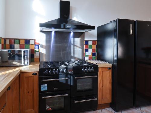 a kitchen with a black stove and a refrigerator at The Power House in Loftus