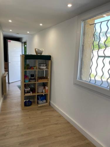 Cette chambre dispose d'une fenêtre et d'une étagère avec de la vaisselle. dans l'établissement Petite maison de ville avec jardin quartier calme, à Nîmes