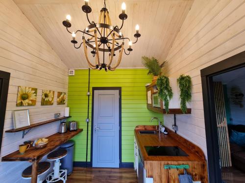 a kitchen with a green wall and a chandelier at The Malvern Hills Courtyard Cabins. (Barbara Cabin) in Great Malvern