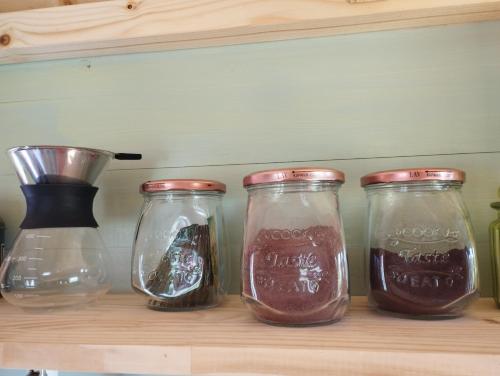 four glass jars sitting on a shelf at La Roulotte romantique du P'tit Buron in Saint-Saturnin
