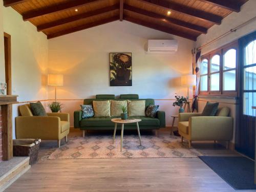 a living room with a green couch and two chairs at A Casa Amarela Guesthouse in São Martinho da Cortiça