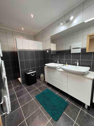 La salle de bains est pourvue de 2 lavabos, d'un miroir et d'un tapis vert. dans l'établissement Maison 3 chambres à Cutry, à Cutry