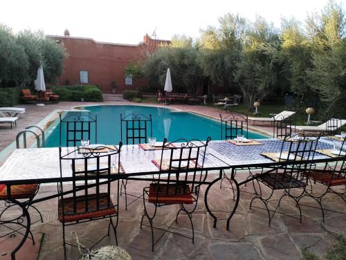 een tafel met stoelen naast een zwembad bij Riad Sidi Hicham in Marrakesh