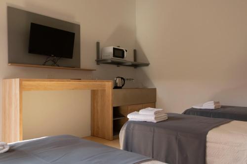 a room with two beds and a flat screen tv at Hotel Cerros del Norte in Tilcara