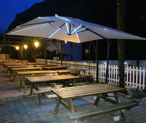una fila de mesas de picnic con un paraguas por la noche en Hotel Miramonti, en Dro