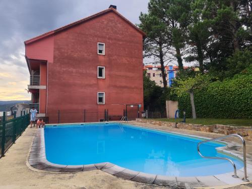 una piscina frente a un edificio rojo en Casa Ferro Portosín, en Portosín