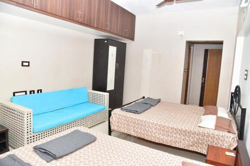 een kamer met 2 bedden en een blauwe bank bij Akash Avenue Soniya Service Apartment in Tirunelveli