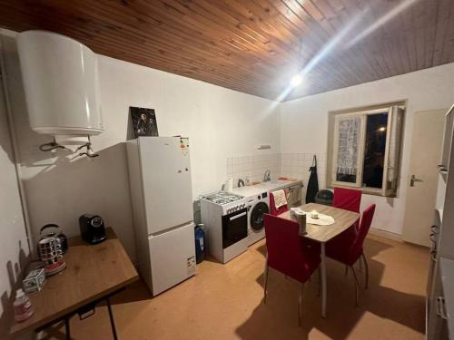 Il comprend une cuisine équipée d'un réfrigérateur et d'une table avec des chaises rouges. dans l'établissement Appartement à Jarny Gare, à Jarny