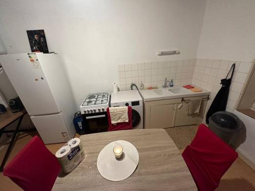 - une cuisine avec une table, des chaises rouges et un évier dans l'établissement Appartement à Jarny Gare, à Jarny