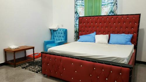 ケンドワにあるAmour Kendwa Beach Houseのベッドルーム1室(赤いヘッドボード、青い枕付きのベッド1台付)